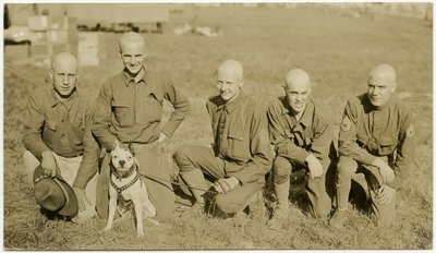 Cinco soldados arrodillados en el césped posando para una foto con un perro con correa de Carl Michel